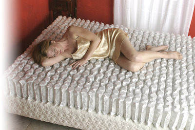 A woman rests on top of the Gold Bond Encased Coil series.